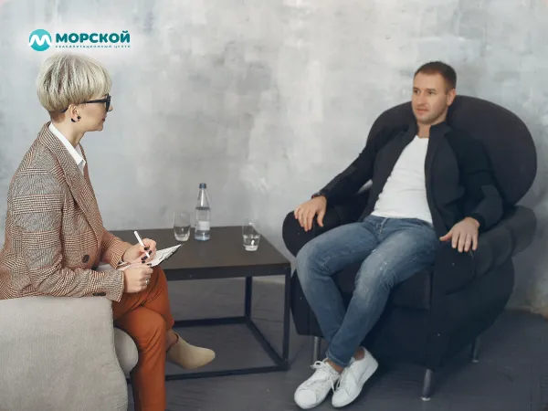 Мужчина общается с психологом Мужчина сидит на приеме у психолога